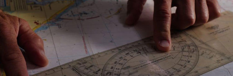 Gros plan sur les mains d'une personne préparant un itinéraire marin à l'aide d'une carte et d'une règle